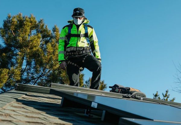 A solar panel worker standing on a roof with solar panels