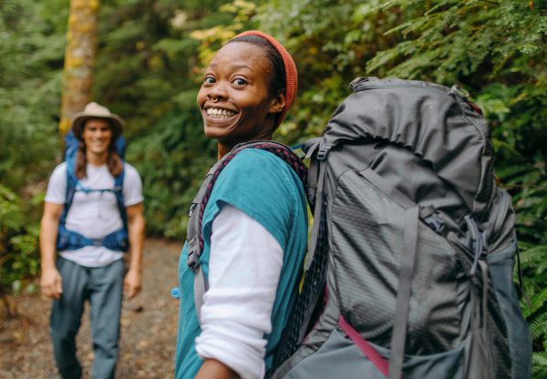 Two people hiking carrying a large backpack